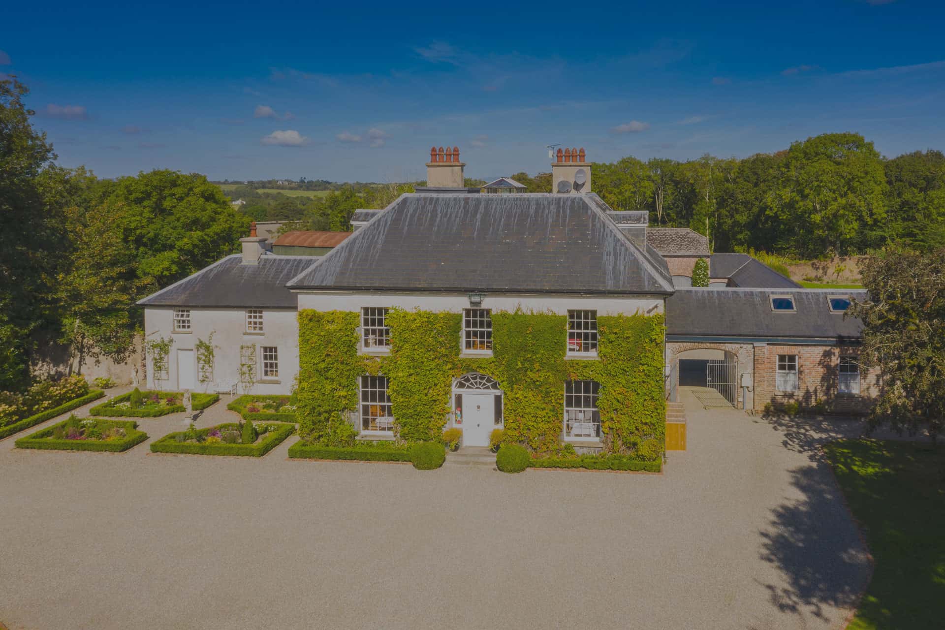 Elegant historic Irish country house with lush greenery and classic architecture.